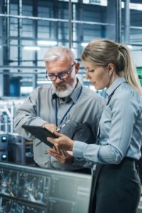 Zwei Ingenieure stehen an der Testanlage und lesen die Testergebnisse auf dem Tablet durch